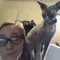 Person with glasses and a hairless cat sitting on their shoulder, both looking at the camera.