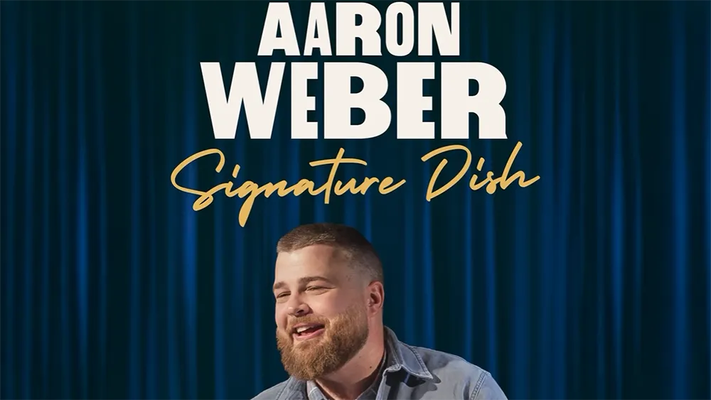 A man smiles under the text "Aaron Weber Signature Dish" on a blue curtain background.