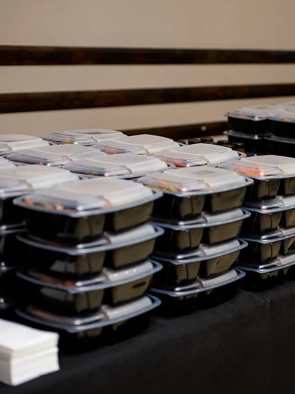 Stacks of black plastic meal prep containers with clear lids arranged on a table.